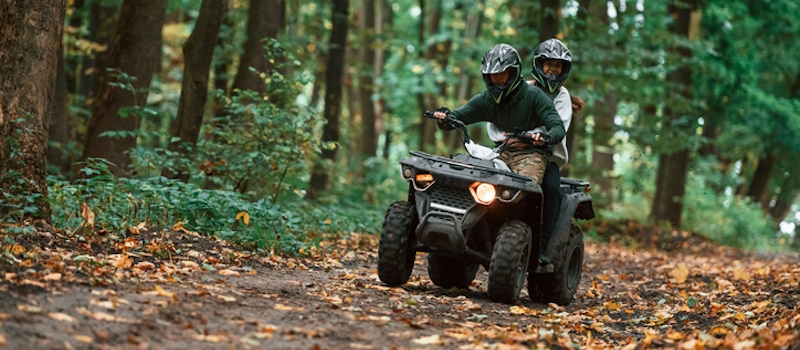 Couple riding an ATV in the woods